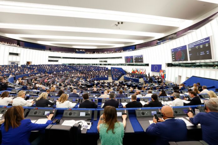 Wide view of the European Parliament hemicycle in Strasbourg during a voting session, with the vote results on large screens