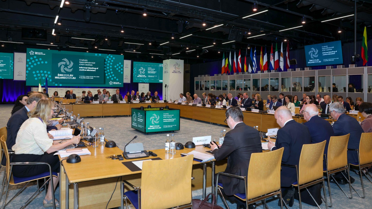 Ministers seated at a large square table in a conference hall at Dublin Castle with EU member state flags