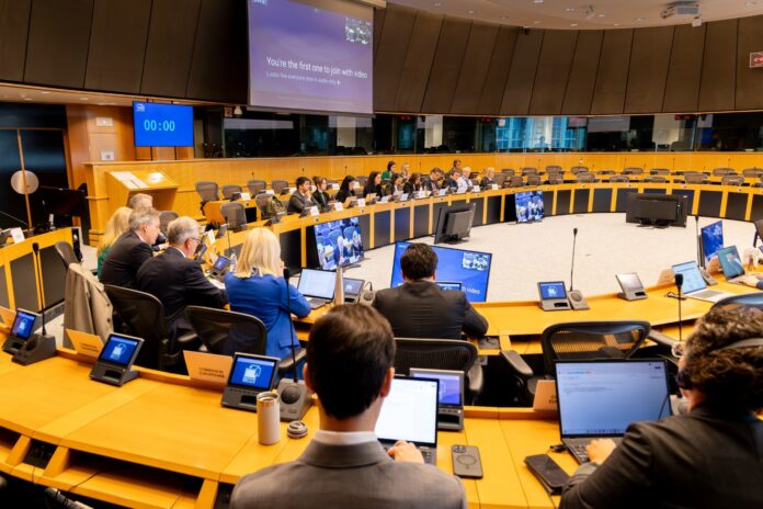 Negotiators seated around a large oval table in a European Parliament meeting room during the Chat Control trilogue